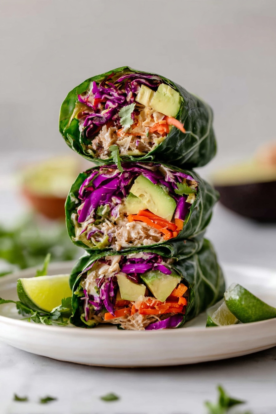 A white round plate on a white marbled surface holds six fresh green lettuce wraps arranged in a circle. Each wrap shows layers inside, starting with deep green lettuce on the outside, then bright orange shredded carrots, purple cabbage, light brown tuna or chicken salad, and topped with slices of light green avocado. To the right of the wraps is a small wooden bowl filled with dark soy sauce with chili flakes and sliced green chilies floating on top. A lime wedge sits next to the bowl. A striped gray and white cloth is partially visible under the plate, and some cilantro leaves appear in the top right corner. Photo taken with an iphone --ar 2:3 --v 7